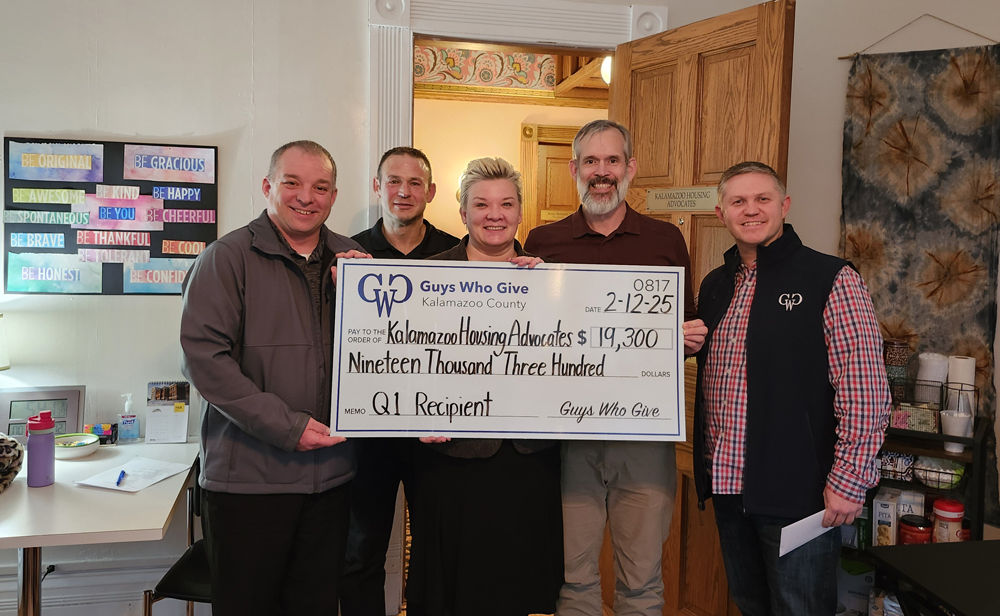 A group of people hold a large check, a donation to KHA.