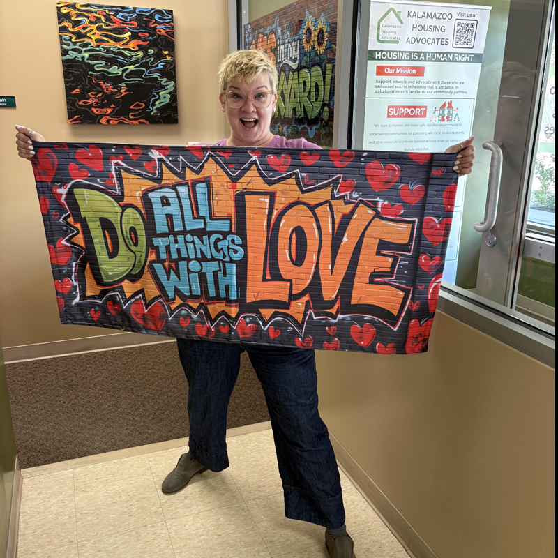 Image of Sarah Cain holding a banner that says 